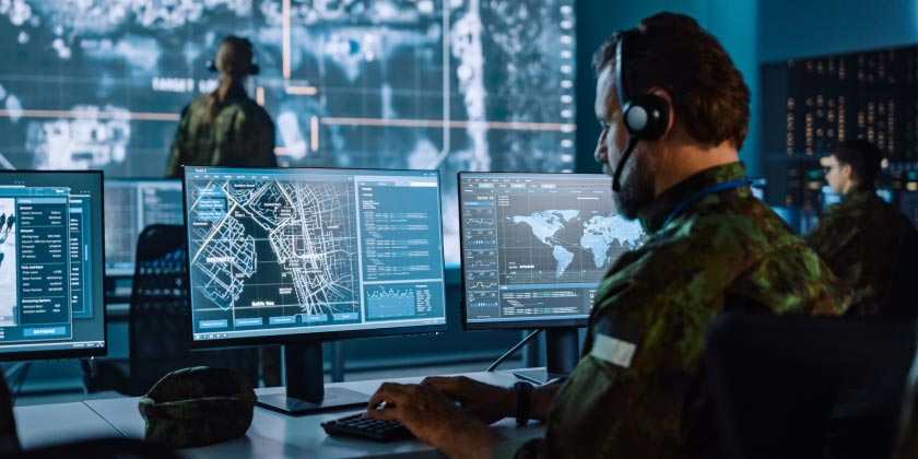 A man in a monitoring centre with futuristic maps up on his screen