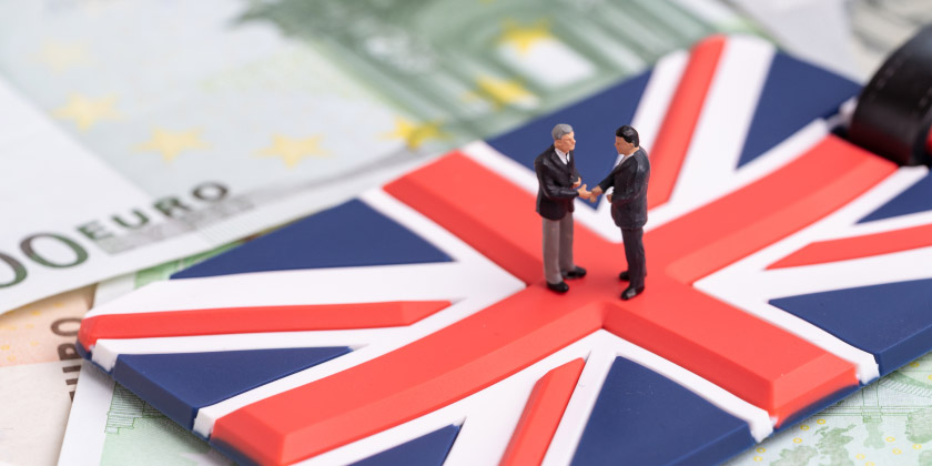Two business men figures shaking hands on a GB flag suitcase label
