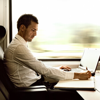 A man working on his laptop on a train A commuter working on his laptop