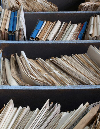 Lots of old files sitting on a dusty shelf Physical data files on a shelf