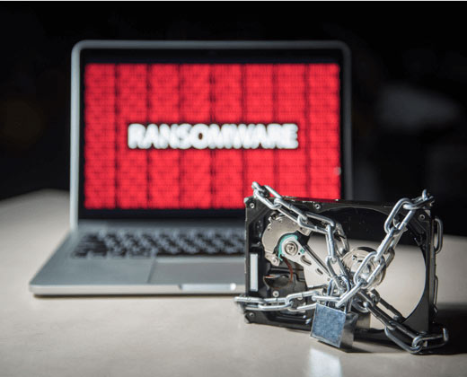 A Physically locked up hard drive next to a laptop with ransomware