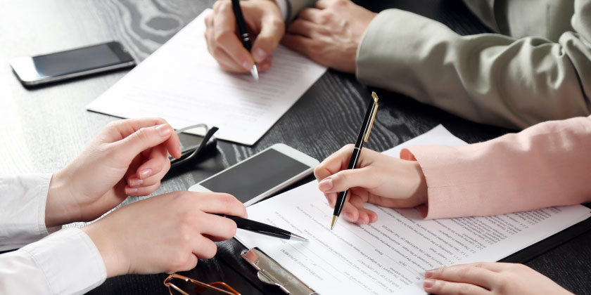 3 people discussing contracts at a desk